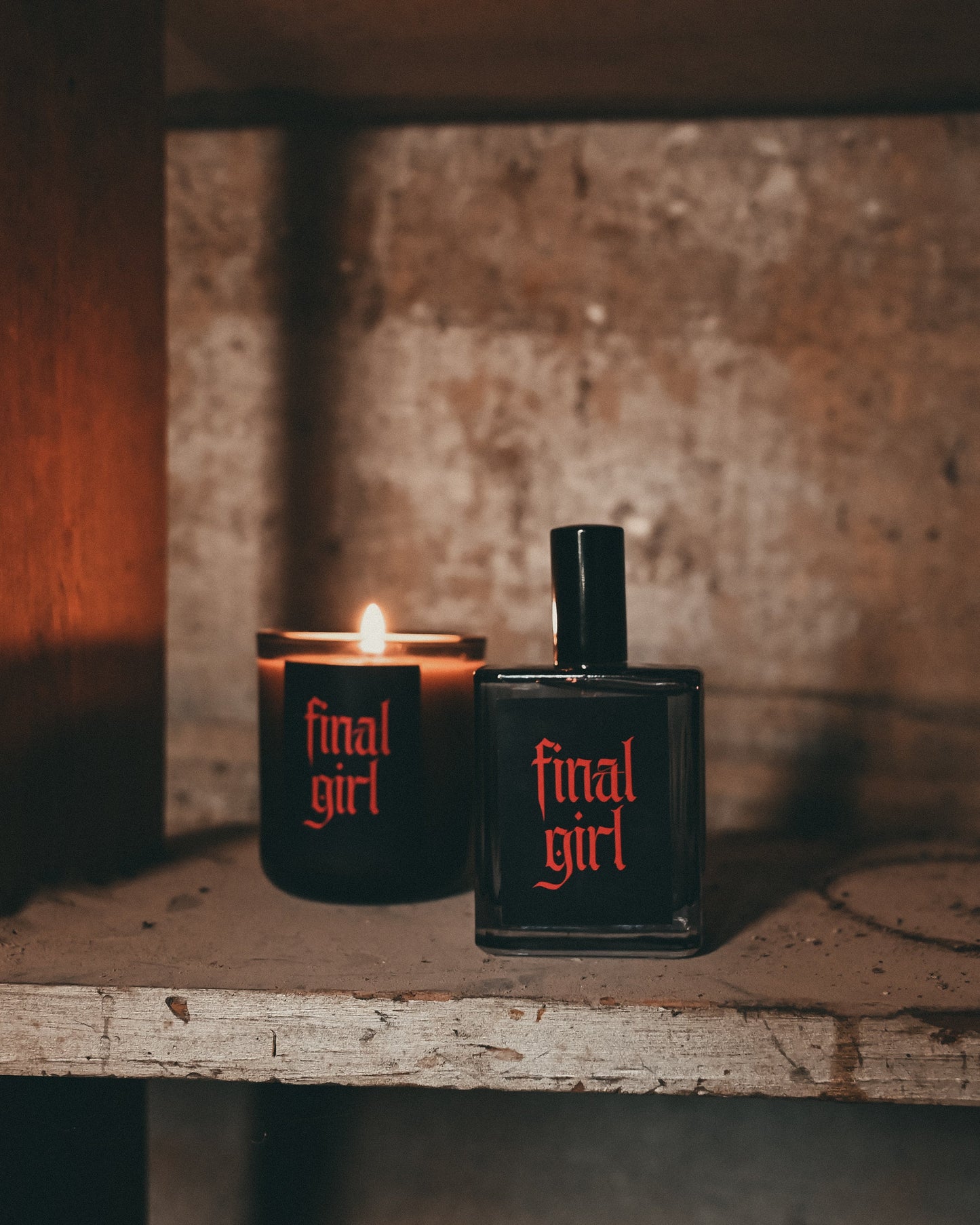 Candle and perfume bottle labeled 'final girl' on a rustic shelf.
