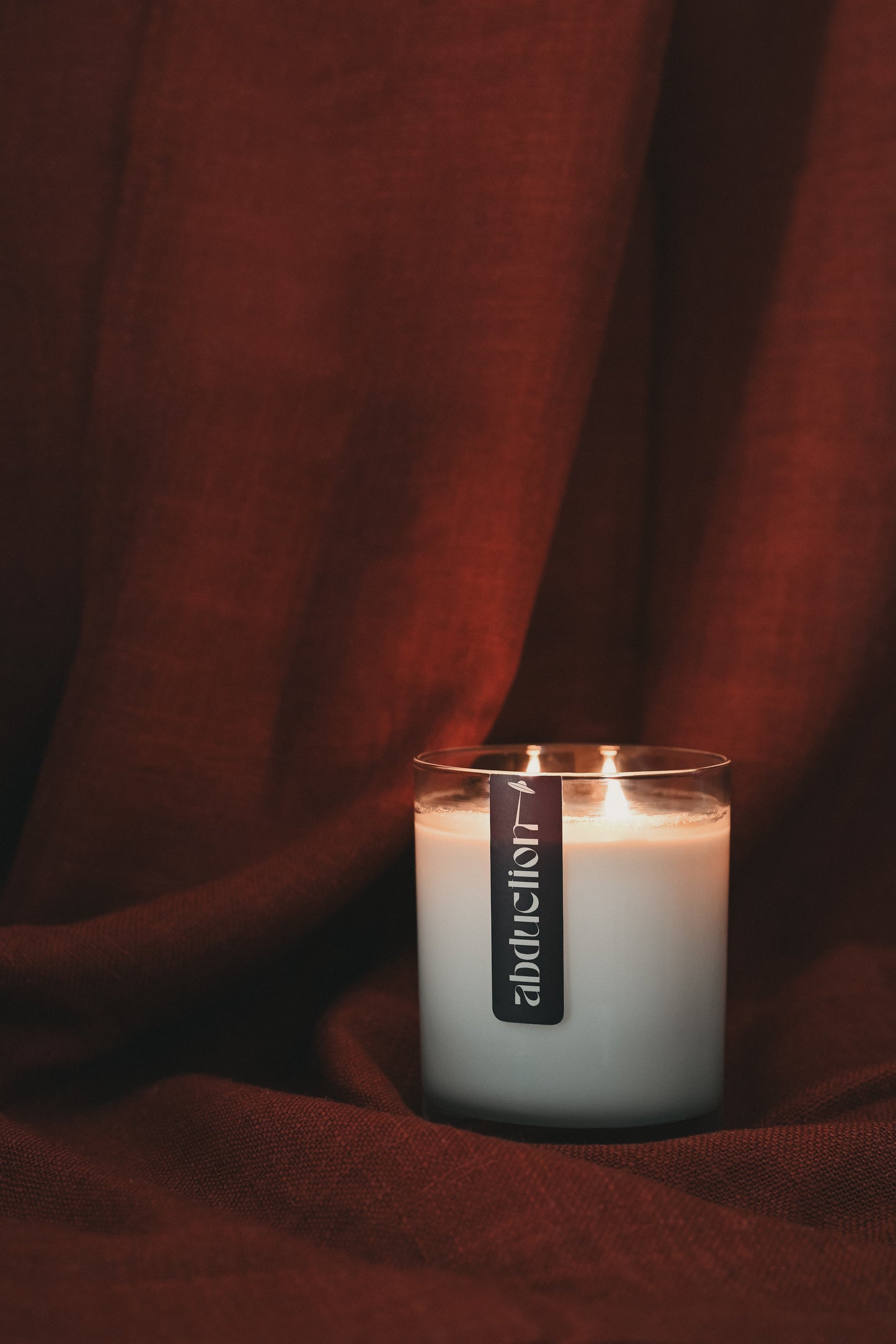 Candle with a label on a dark red fabric background