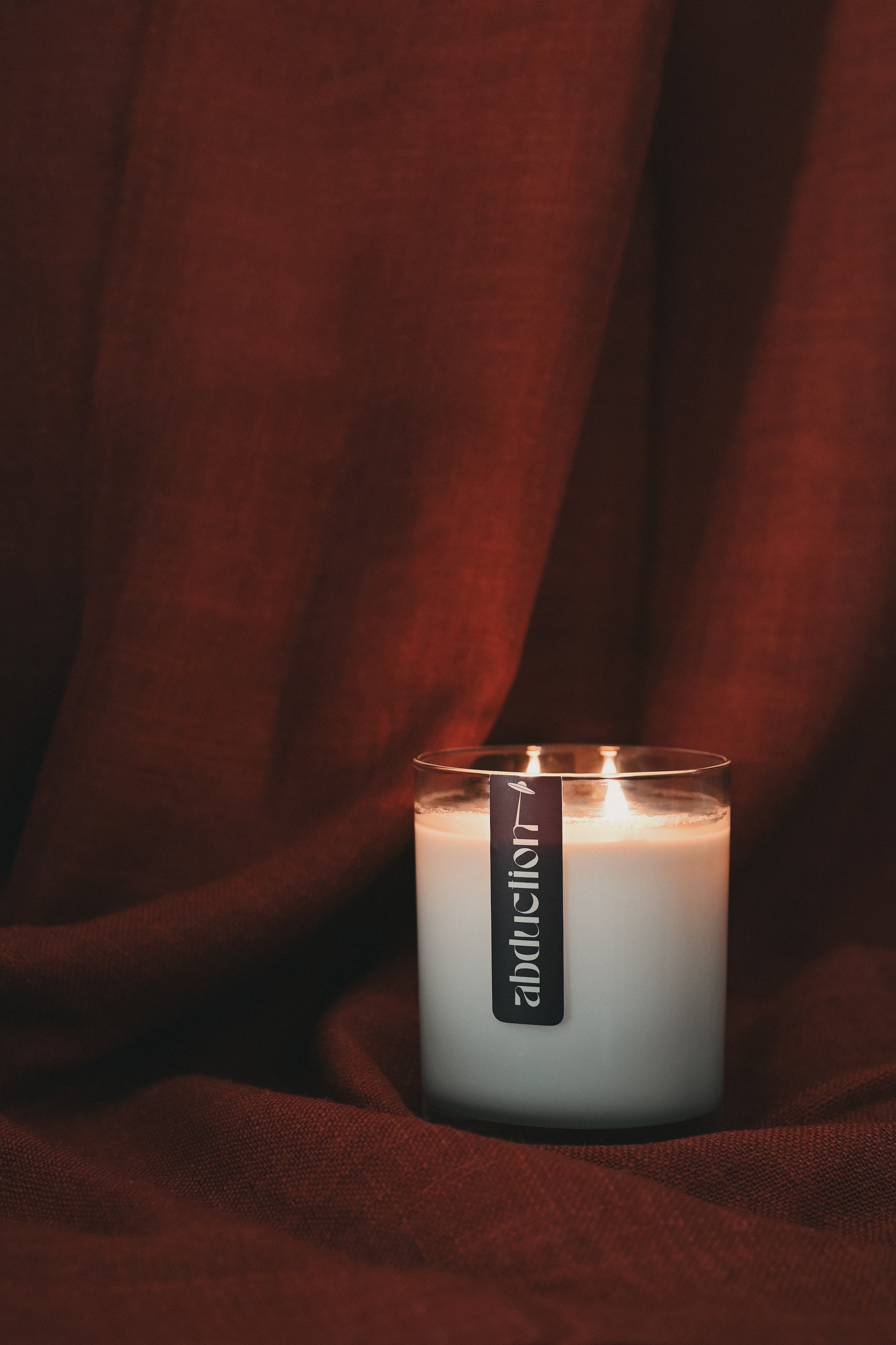 Candle with a label on a dark red fabric background